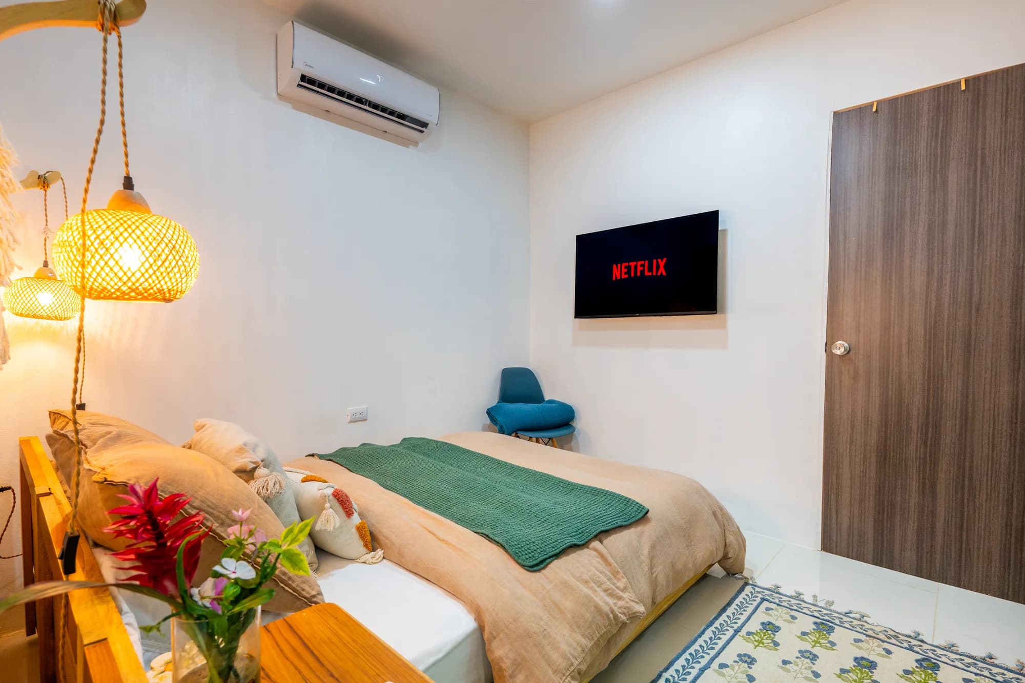Casita Green Iguana bedroom with woven globe pendant lamps, tan bedding, and wall-mounted TV