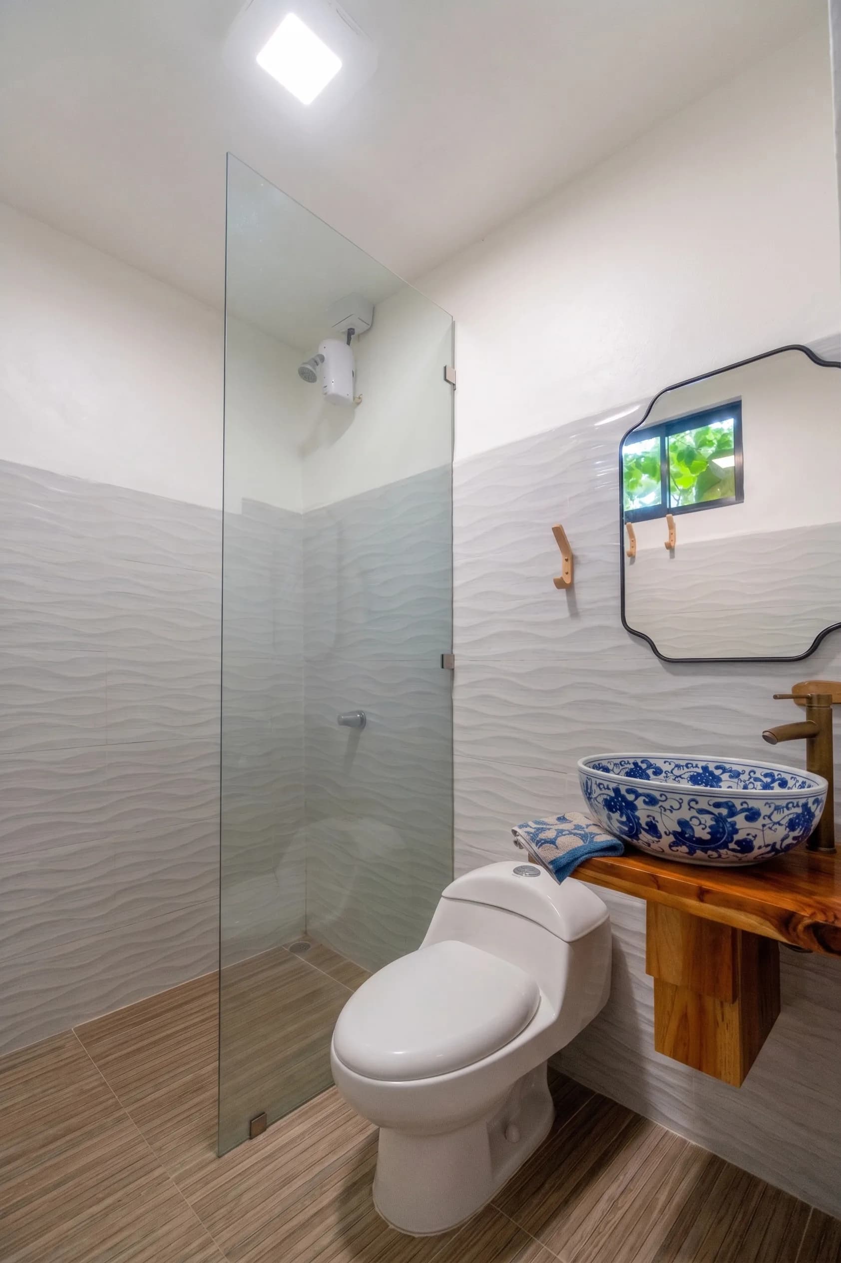 Morpho House bathroom with walk-in shower, wood vanity, and blue Chinoiserie vessel sink