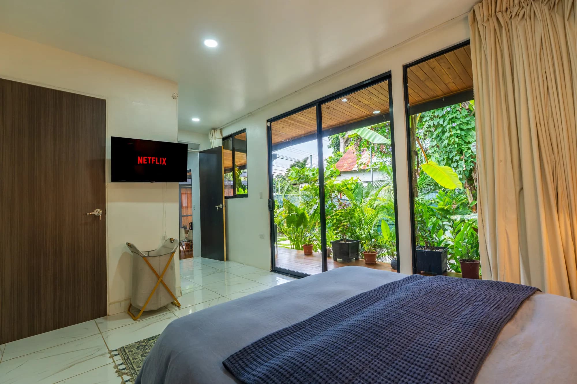 Morpho House bedroom with garden views, wall-mounted TV, and blue bedding
