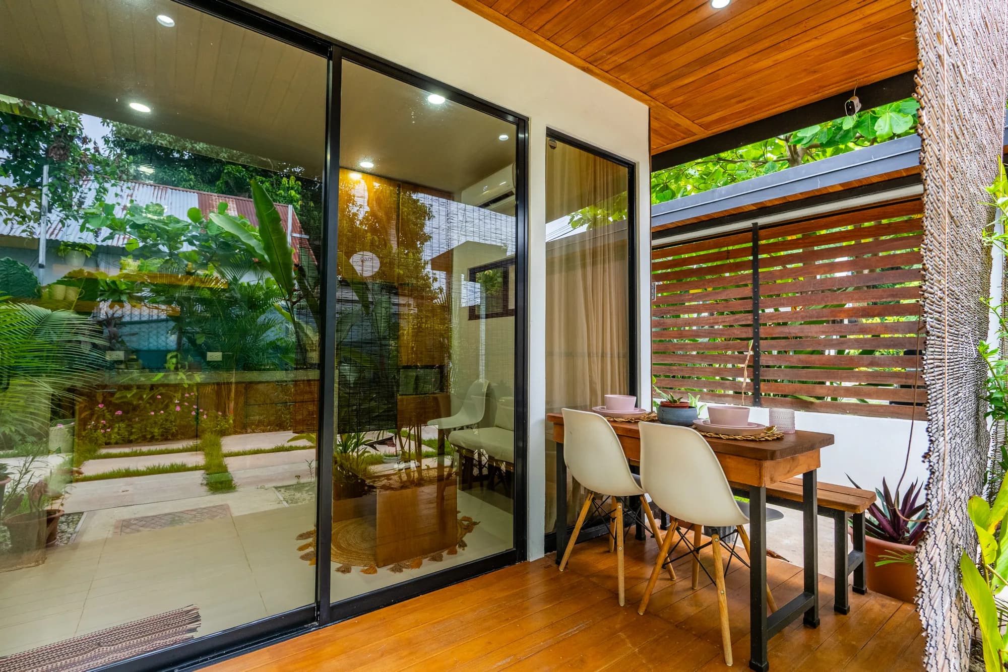 Covered outdoor dining patio at Morpho House on a wood deck surrounded by tropical gardens