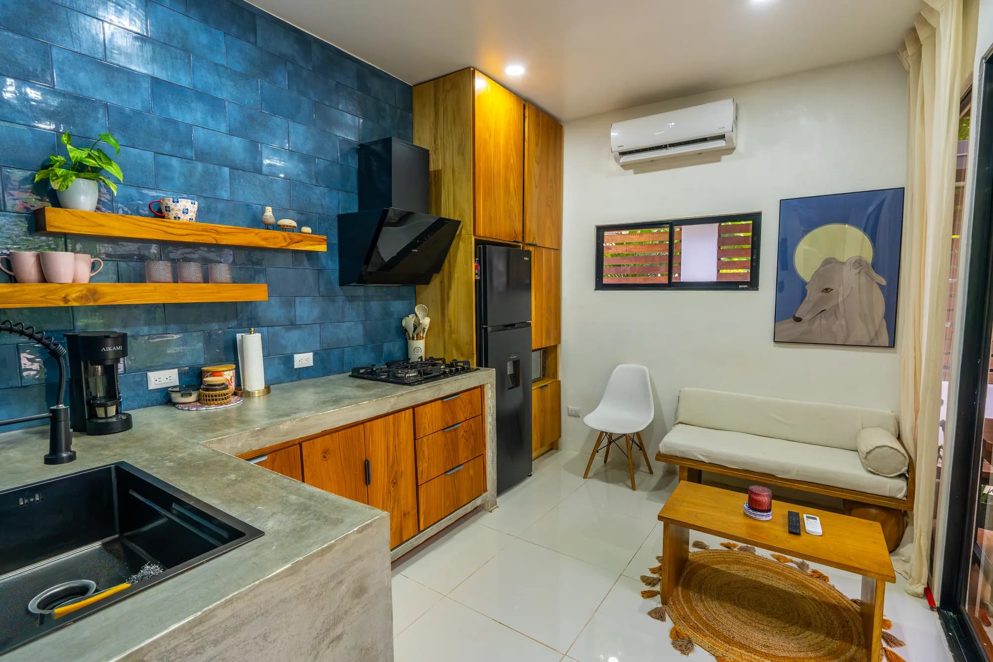 Open-plan studio living area at Morpho House with kitchen, daybed, and garden views