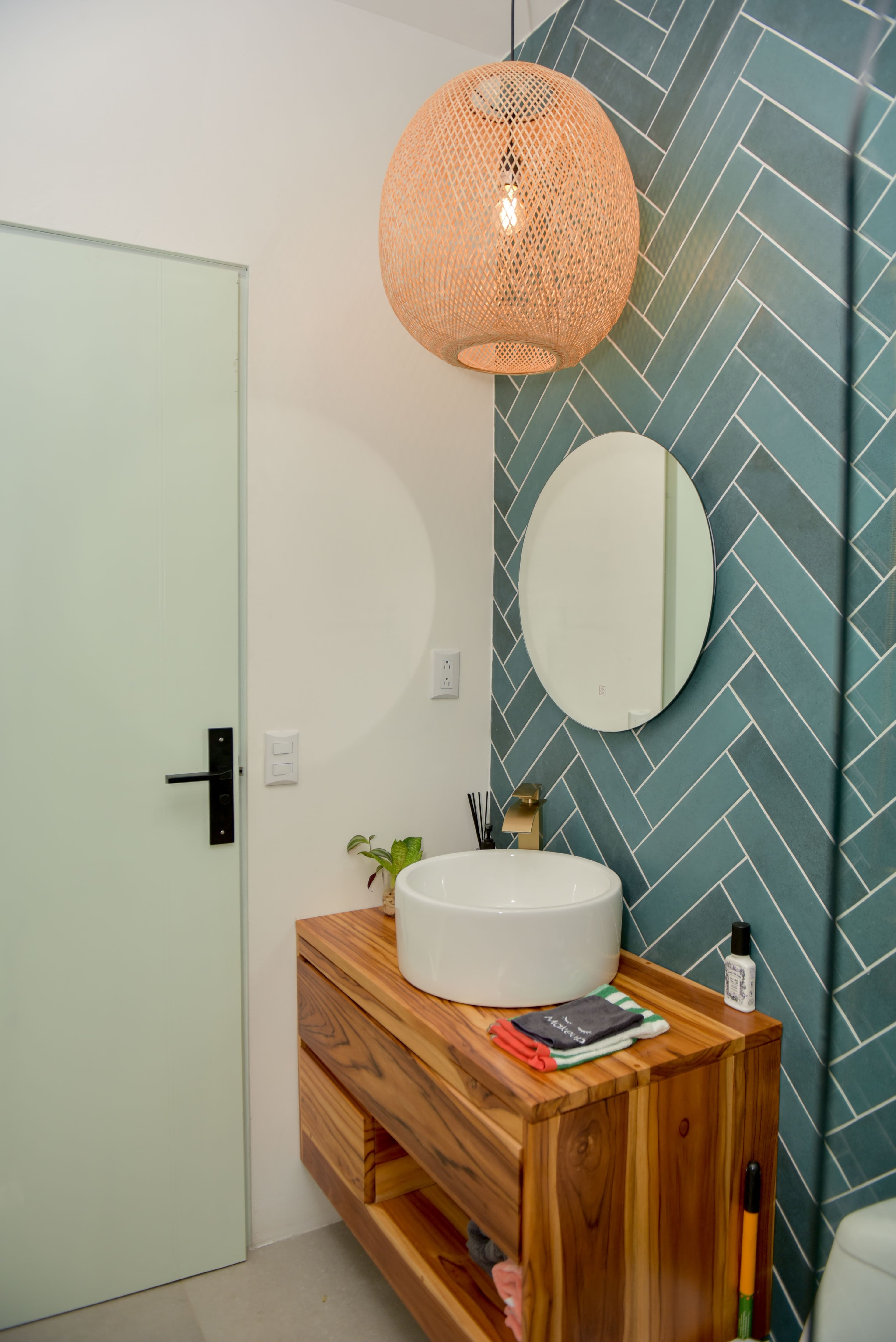 Ground-floor full bathroom shower and vanity with teal herringbone tile